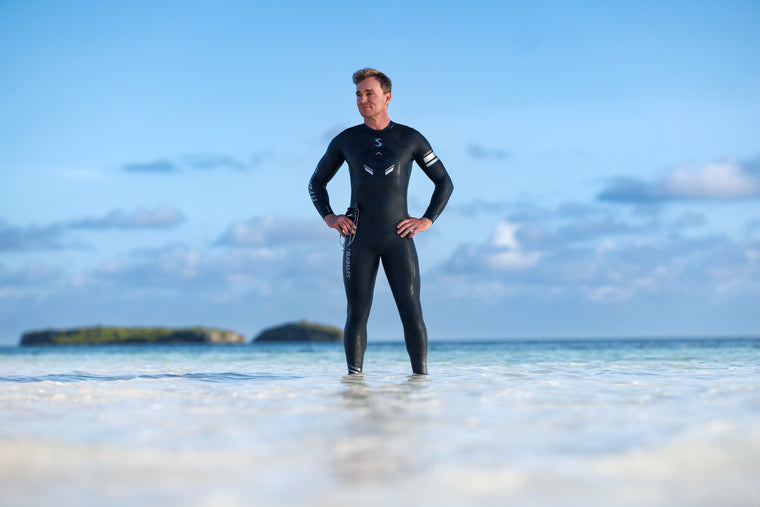 Stefan Laursen standing in shallow water wearing a Synergy wetsuit